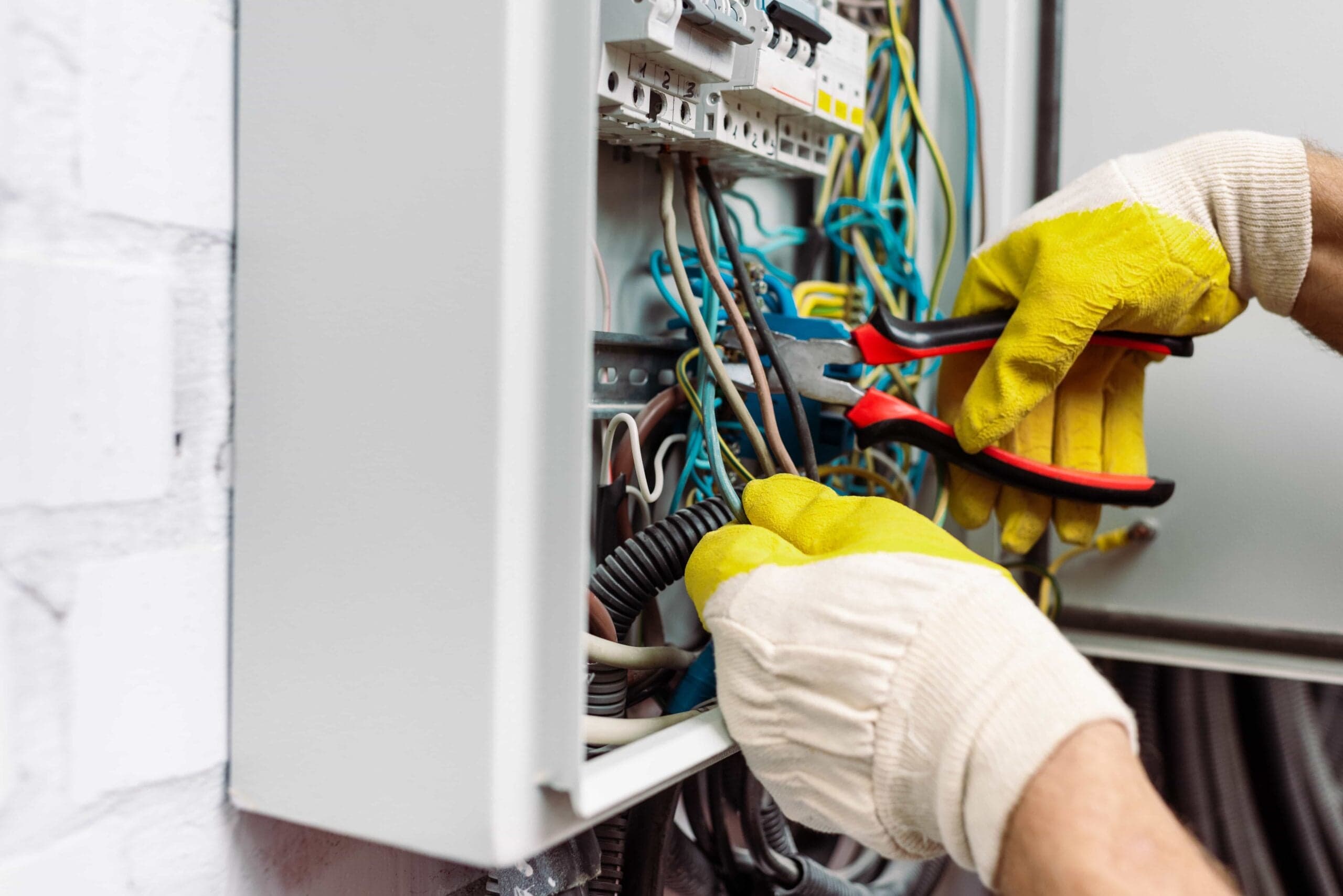 Close-up of a professional electrician using pliers to repair wiring in an Electric Panel Installation Pelican Bay
