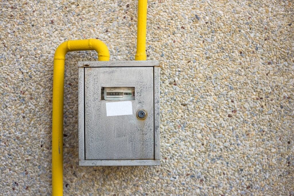 A close-up view of a metal gas meter box and yellow piping, part of our professional gas line services in Ocala, FL.