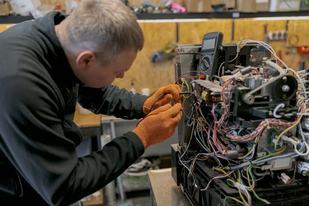 Male electrician repairing with terms of service of Tropical Electric & Lighting.